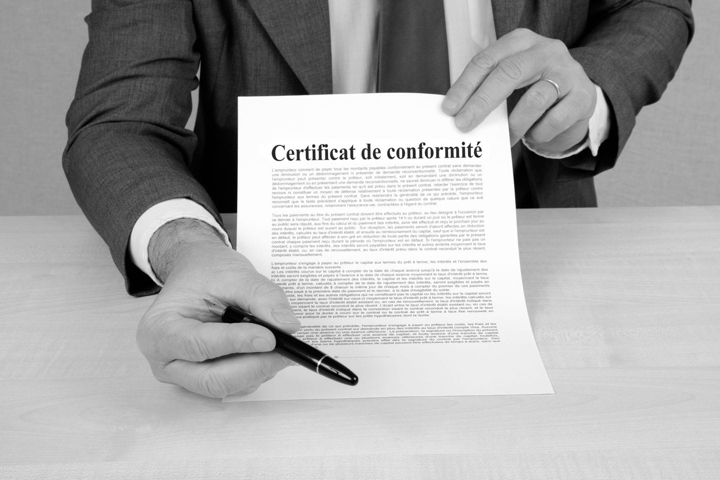 Homme en costume présentant un certificat de conformité avec un stylo.