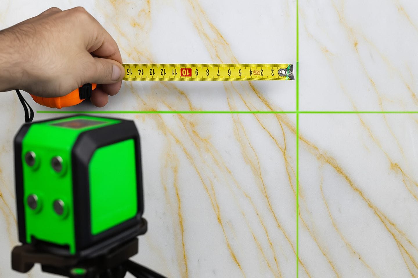 Photo d'une main tenant un metre devant une tranche de matériau